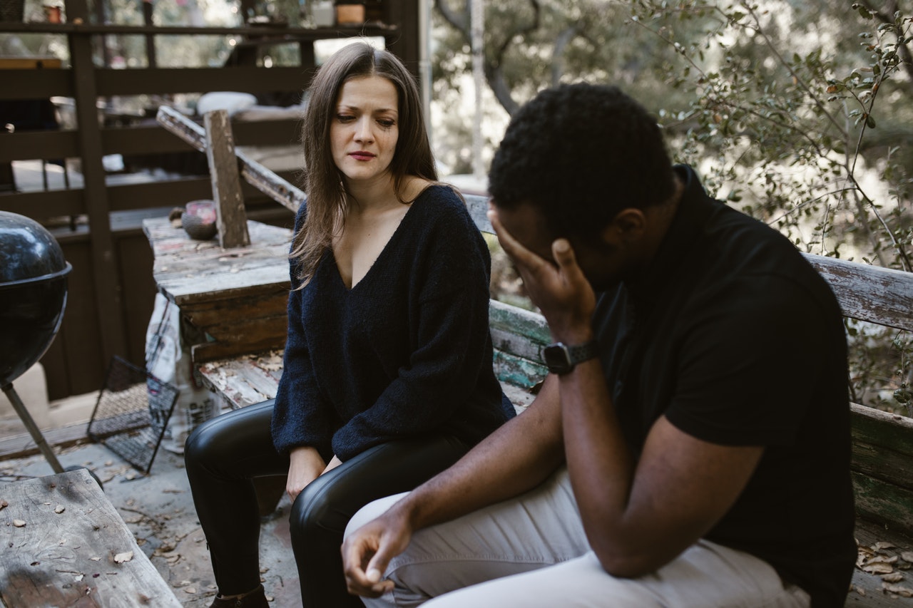 man and woman sitting on bench crying