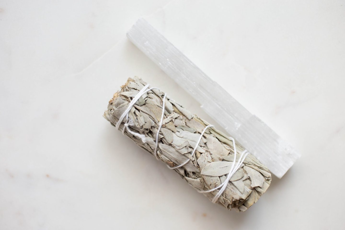 selenite wand and sage against white background
